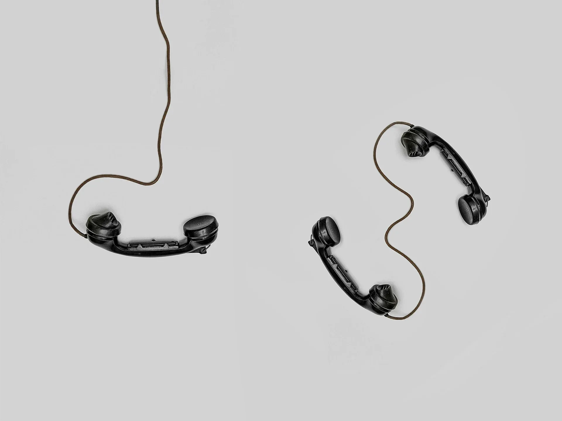 Receptoare telefonice retro pe fundal gri deschis, simbol al comunicării.